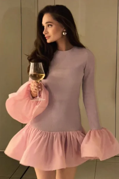 Woman wearing long sleeve knit mini dress with puffy hem and flare cuffs