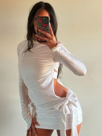 Woman in white cutout mini dress with bows and long sleeves