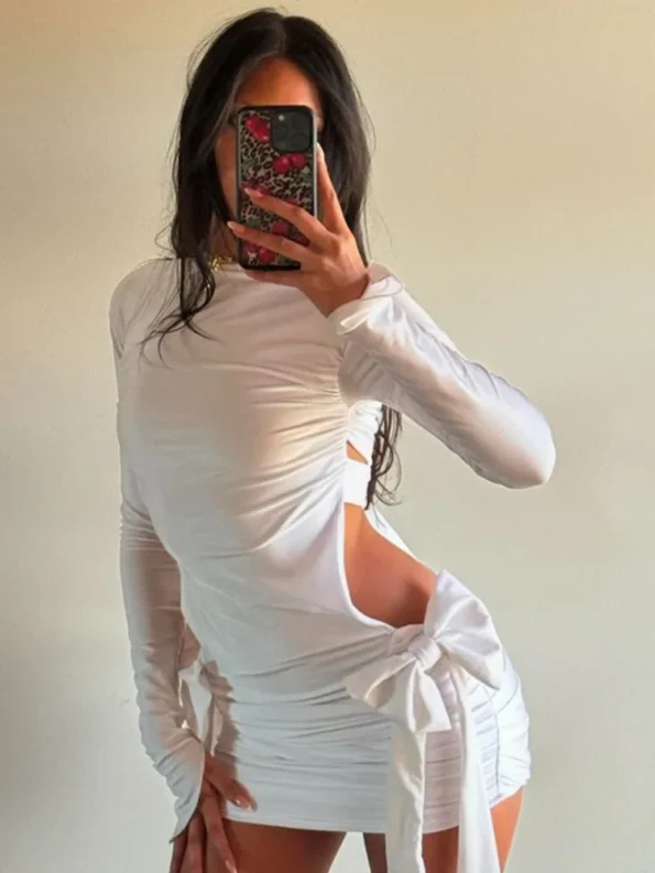 Woman in white cutout mini dress with bows and long sleeves